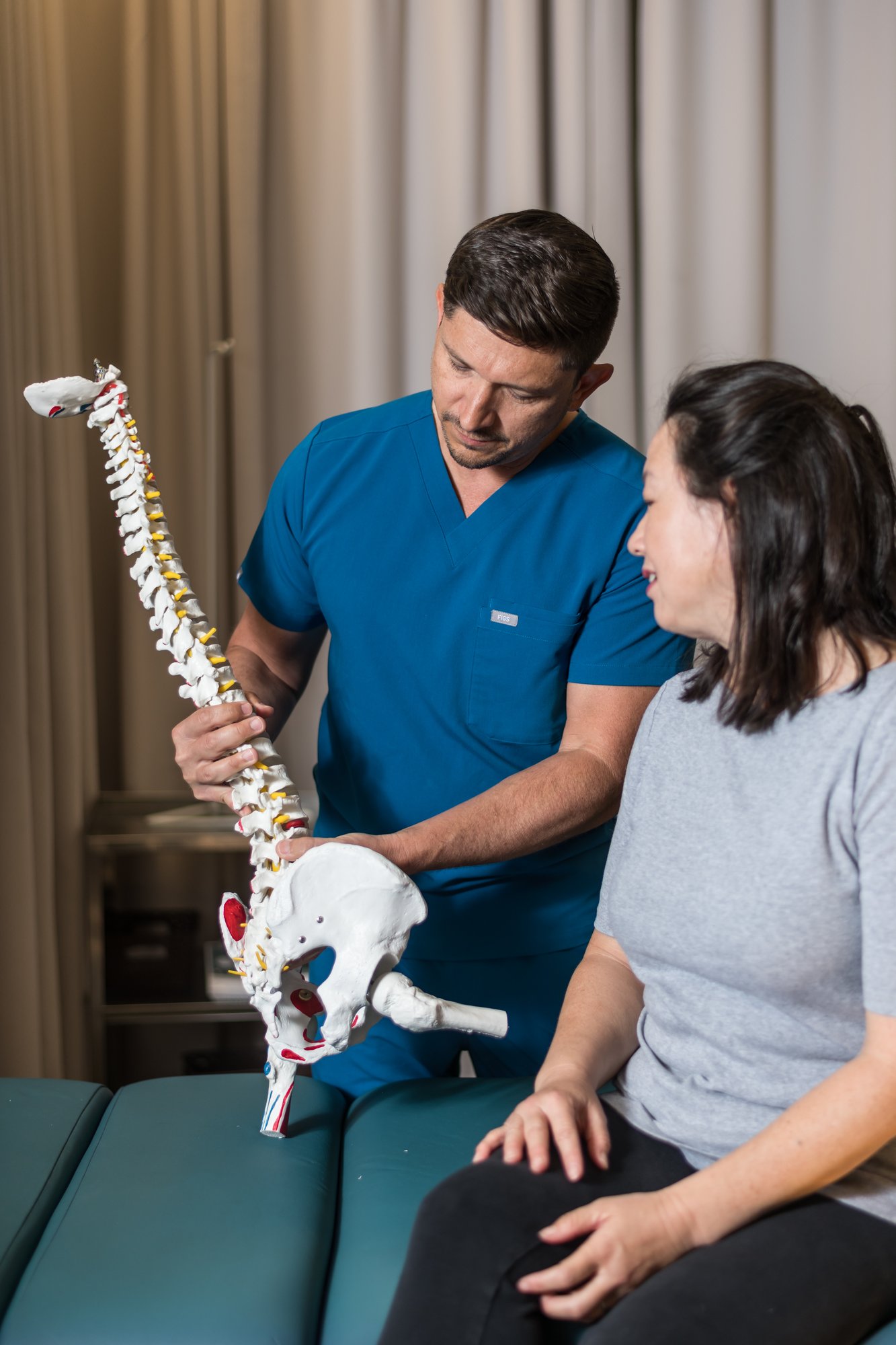 Dr. Donald Thigpen explaining spinal anatomy to a patient using a spine model